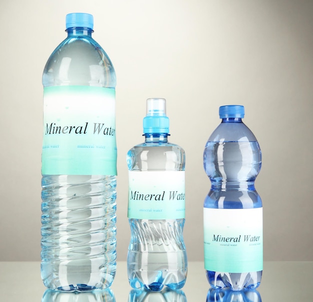 Diferentes botellas de agua con etiqueta sobre fondo gris