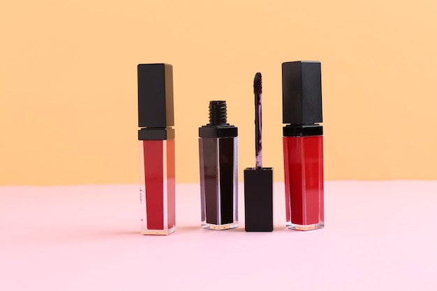 Diferentes brillos para los labios y aplicador en fondo de color
