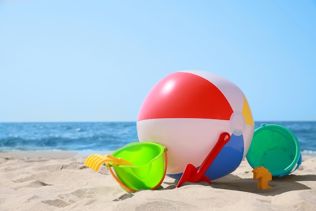 Diferentes brinquedos de areia e bola de praia perto do mar