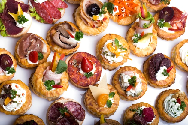 Diferentes canapés com salmão defumado, tomate cereja e mussarela servidos em uma mesa