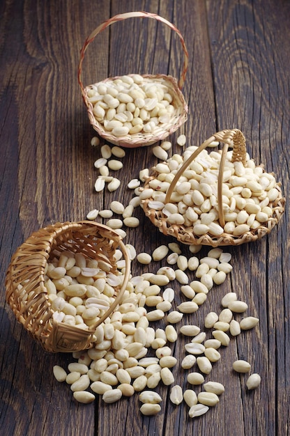Diferentes cestas de vime com amendoim em um fundo de madeira
