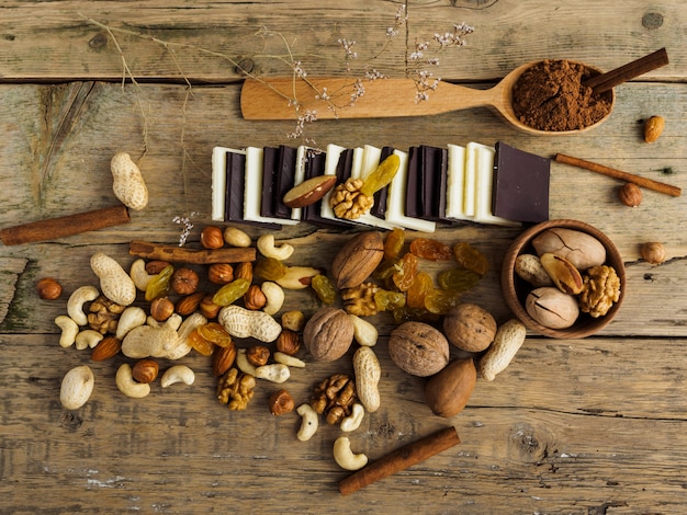 Diferentes chocolates, nozes e outros doces em uma mesa de madeira