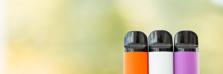 Diferentes cigarrillos electrónicos desechables sobre fondo verde de verano Concepto de fumar electrónico