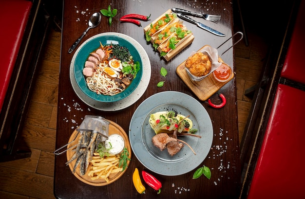 Diferentes comidas coloridas en una mesa de madera oscura en el restaurante