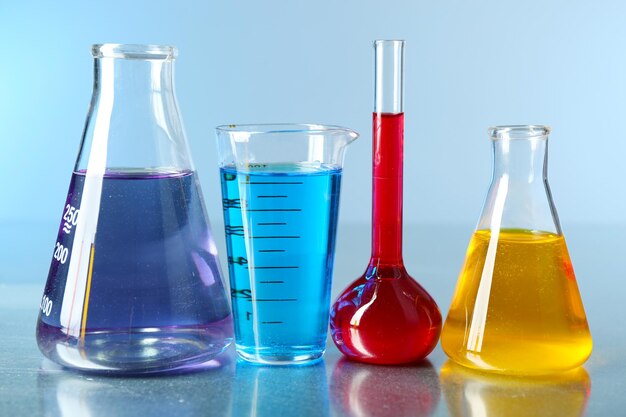 Diferentes cristalería de laboratorio con líquido colorido sobre fondo de color