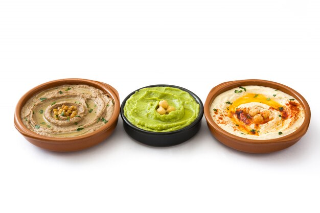 Diferentes cuencos de hummus Hummus de garbanzos, hummus de aguacate y hummus de lentejas aislado en blanco