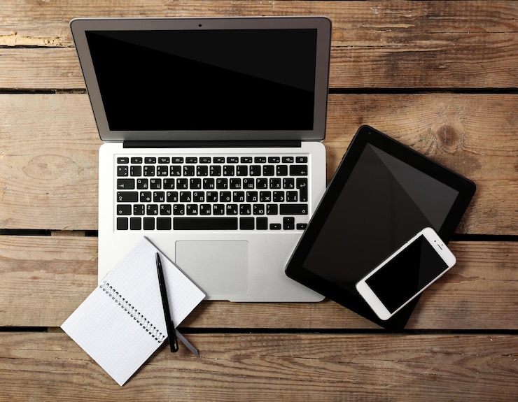 Foto diferentes dispositivos modernos con cuaderno y bolígrafo en una mesa de madera