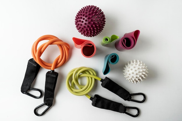 Diferentes equipamentos coloridos para exercícios de fitness e esporte halteres laranja e expansores bolas de fitness e bandas deitadas em um fundo branco