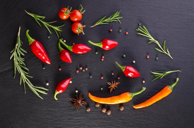 Diferentes especiarias com tomate e pimentão em um fundo preto