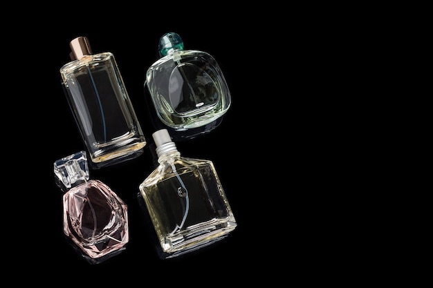 Diferentes frascos de perfume con reflejos sobre superficie negra