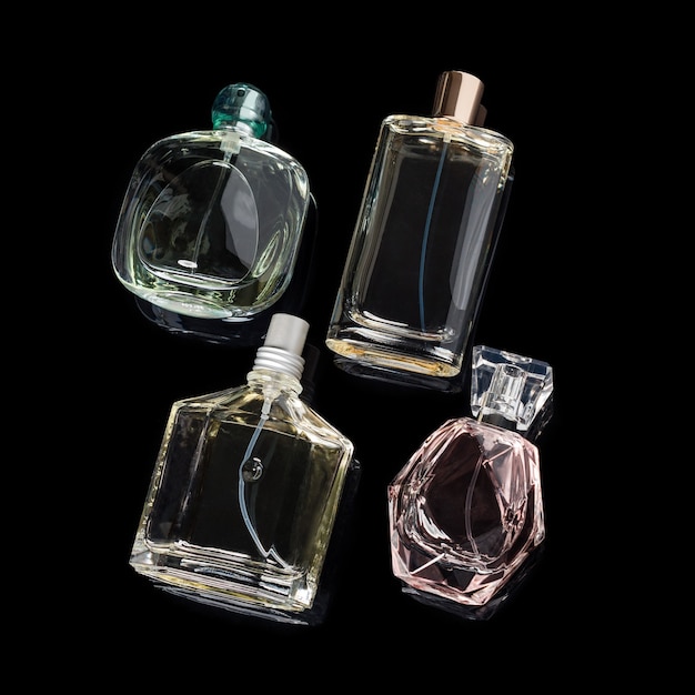 Diferentes frascos de perfume con reflejos sobre superficie negra