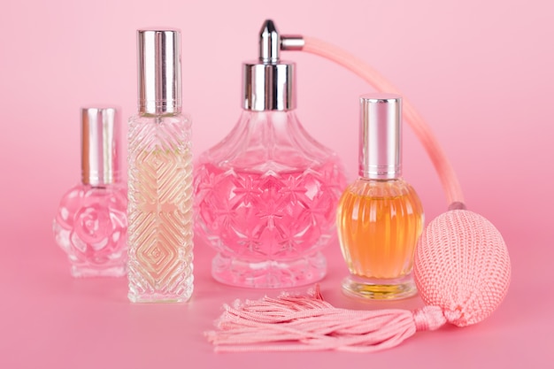 Diferentes frascos de perfume transparente sobre fondo rosa. Botellas de esencia aromática