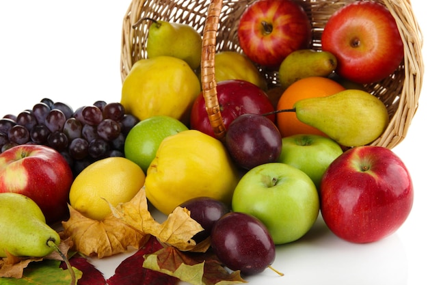 Diferentes frutas con cesta y hojas amarillas aisladas en blanco