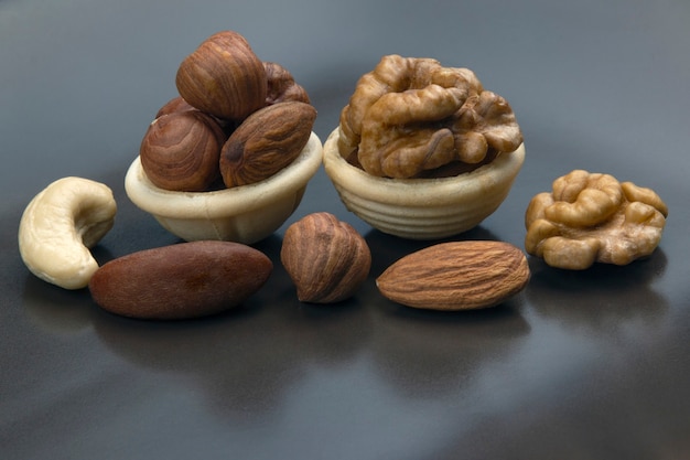 Diferentes frutos secos en una canasta de gofres sobre una mesa gris. Alimentos saludables con vitaminas.