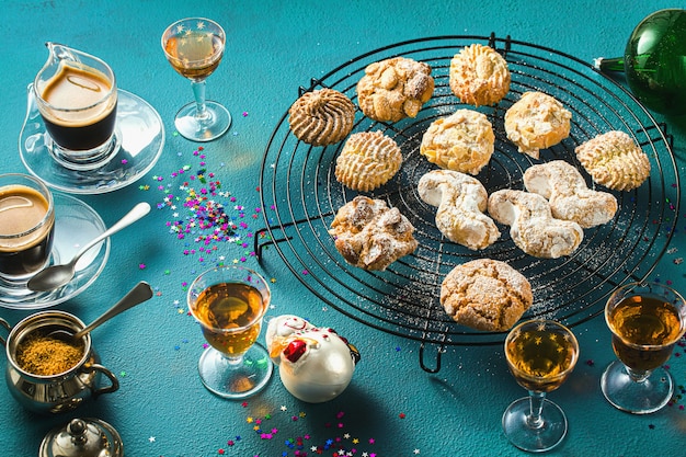 Diferentes galletas de almendras caseras italianas clásicas con café expreso y vasos de licor dulce sobre la mesa, decoración navideña