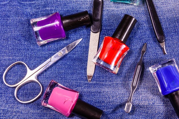 Diferentes herramientas de manicura y esmaltes de uñas en los blue jeans Vista superior