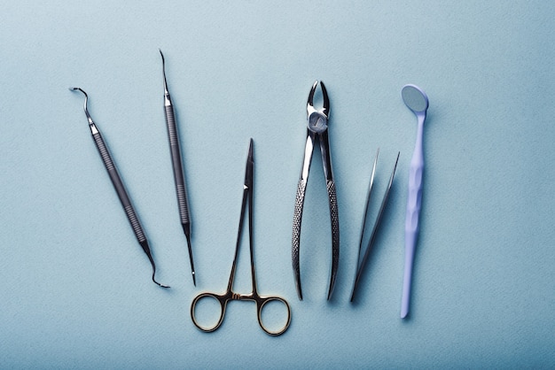 Foto diferentes instrumentos dentales de acero sobre fondo azul claro