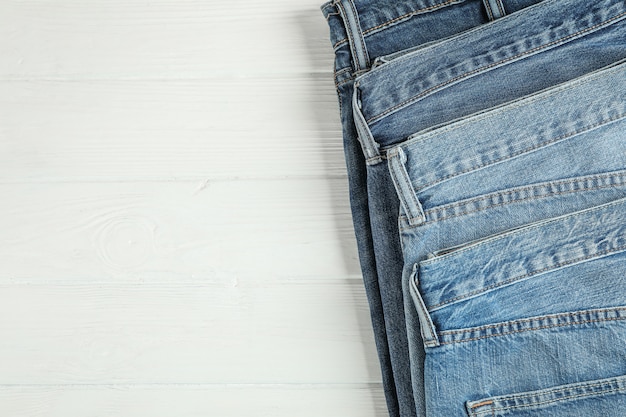 Diferentes jeans doblados sobre un fondo blanco de madera, espacio para texto