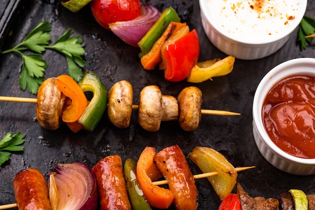 Diferentes kebabs grelhados com carne, cogumelos, salsichas e vegetais no espeto