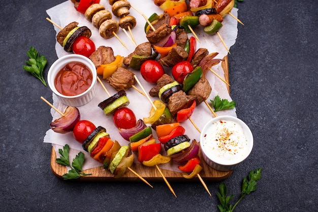 Diferentes kebabs a la plancha con carne, champiñones, salchichas y verduras en brochetas