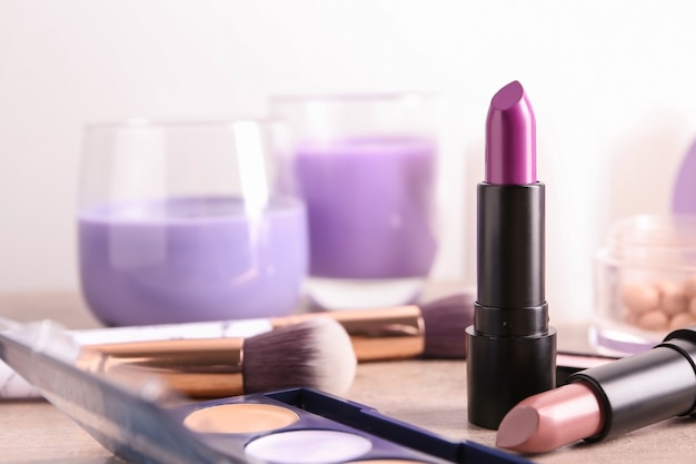 Diferentes lápices labiales y otros cosméticos en la mesa.