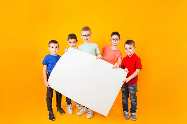 Los diferentes niños pequeños sostienen un gran libro blanco.