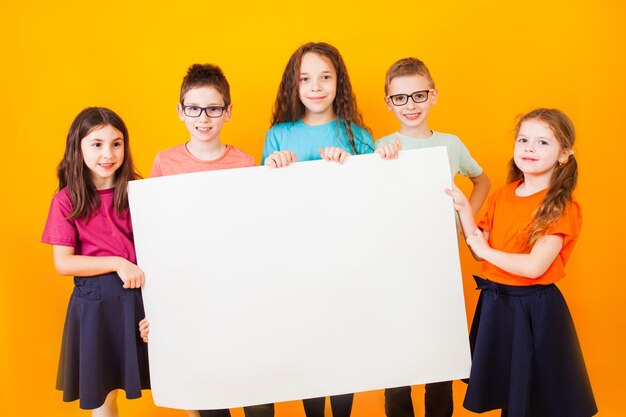 Los diferentes niños pequeños sostienen un gran libro blanco.