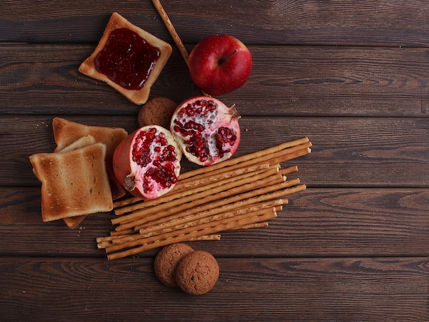 Diferentes pães de pão fresco e espigas de trigo em um fundo marrom vintage