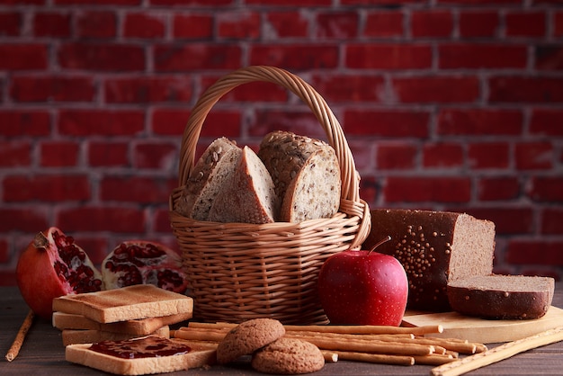 Diferentes pães de pão fresco e espigas de trigo em um fundo marrom vintage