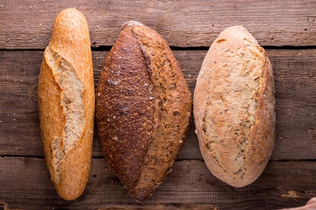 Diferentes pães e pães frescos na mesa de madeira