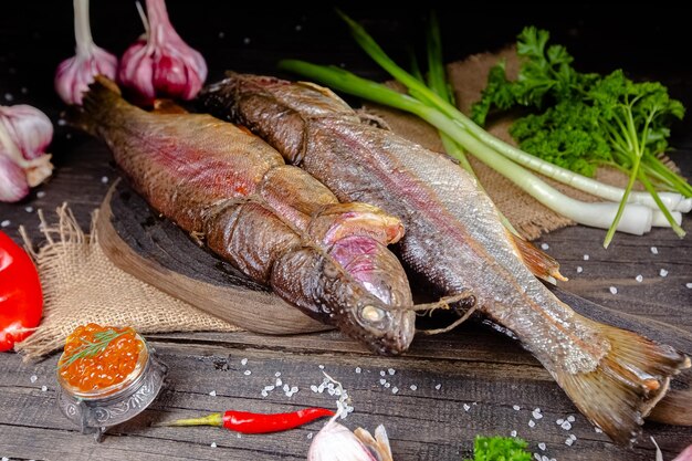 diferentes peces de río ahumados en el mar yace en un rustk atornillado en una tabla de cortar y una mesa, las cuerdas,