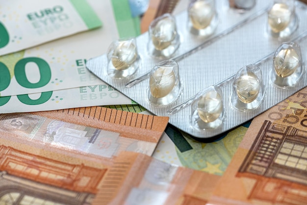 Diferentes píldoras o cápsulas de medicamentos sobre billetes de euro