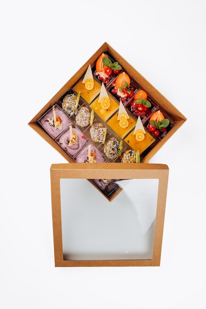 Diferentes porciones de postres con mermelada y fruta en una caja están listas para su entrega