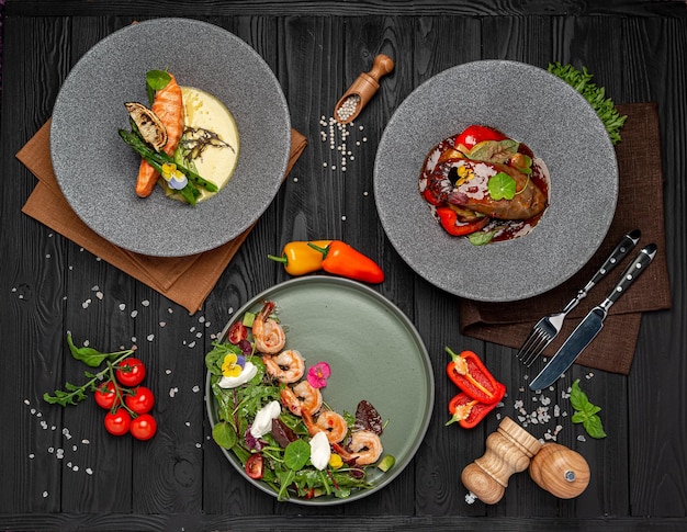 Diferentes pratos na mesa no restaurante salada de camarão bife de língua de boi salmão grelhado