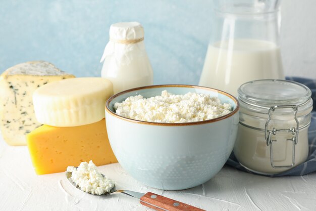 Diferentes productos lácteos en mesa blanca sobre fondo azul.