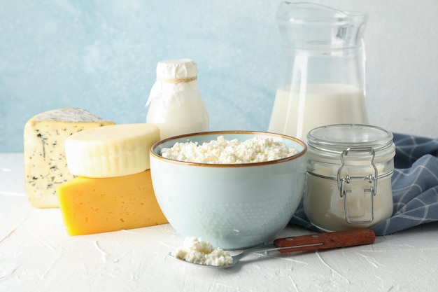 Diferentes productos lácteos en mesa blanca sobre fondo azul.