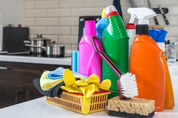 Diferentes produtos e itens para limpeza na bancada da cozinha.