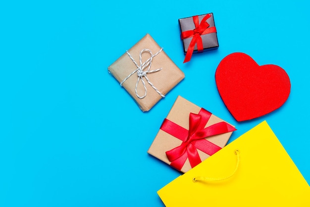 Diferentes regalos, juguetes en forma de corazón y bolsa amarilla sobre el hermoso fondo azul.