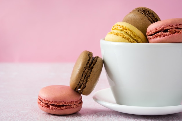 Diferentes sabores de macarons em um espaço de cópia de caneca