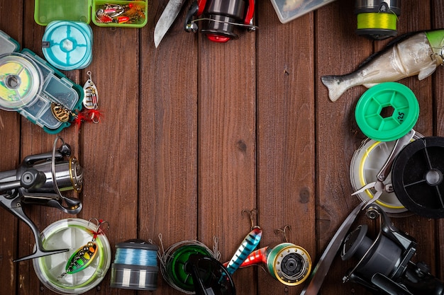 Foto diferentes tacos de pesca con señuelos y carretes sobre fondo marrón de madera con lugar para el texto. diseño para publicidad y publicación.