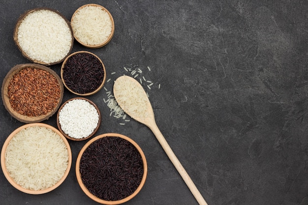 Diferentes tipos de arroz en cuenco de cerámica. Arroz blanco en cuchara de madera. Endecha plana