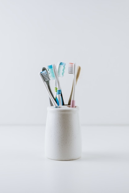 Foto diferentes tipos de cepillos de dientes en una taza blanca.