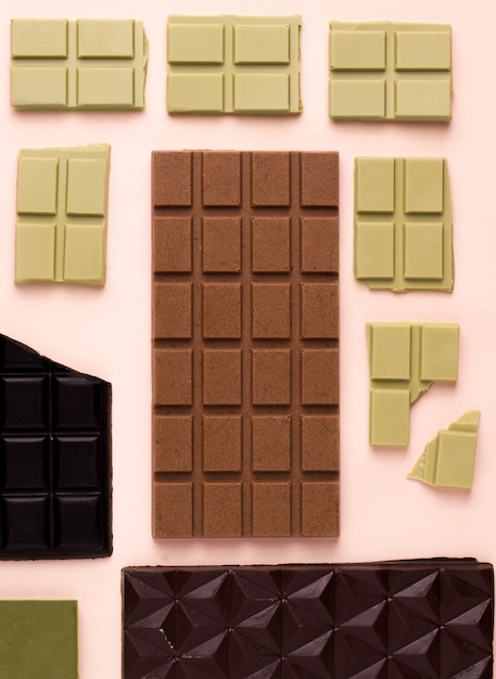 Diferentes tipos de chocolate sobre un fondo rosa. Vista desde arriba