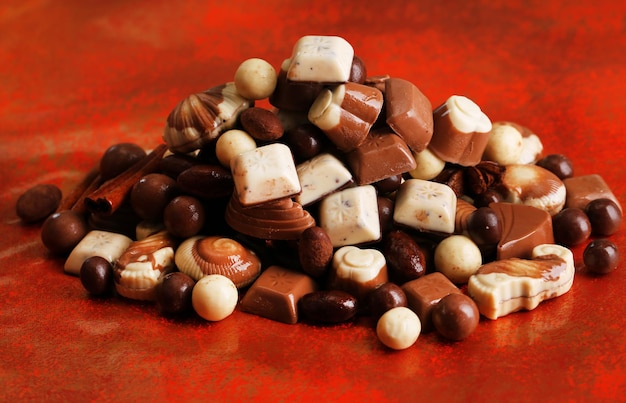 Foto diferentes tipos de chocolates sobre fondo rojo.