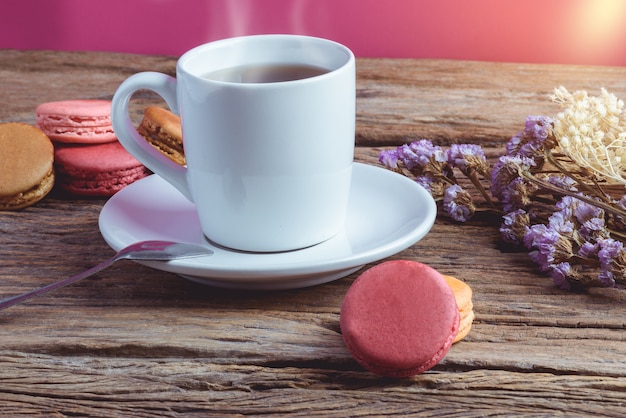 Diferentes tipos de color de macarons con taza de té caliente en viejo fondo de madera de grunge