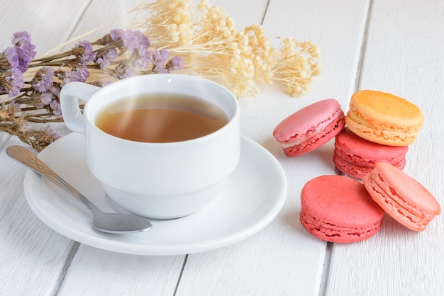 Diferentes tipos de colores de macarrones con taza de té caliente