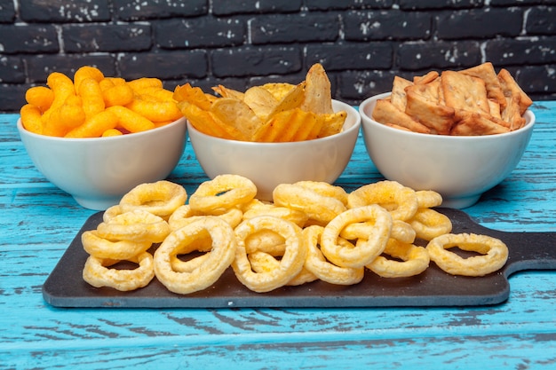 Diferentes tipos de comida chatarra, palitos salados, galletas saladas en la mesa de madera en bodegones