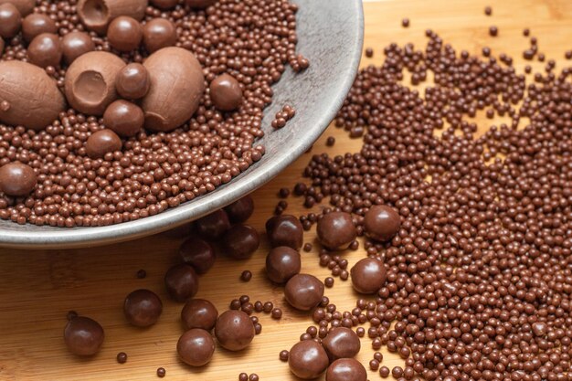 Diferentes tipos de bolas de chocolate em uma tigela cinza em uma mesa de madeira