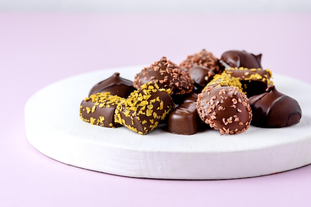 Diferentes tipos de bombons de chocolate no fundo rosa Sobremesa saborosa de bombons de chocolate acima