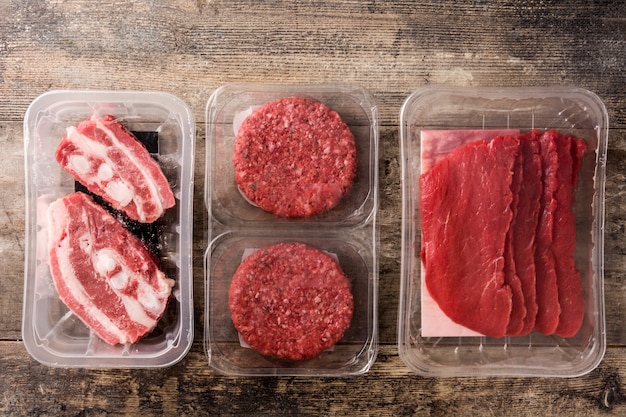 Diferentes tipos de carne embalados em plástico na mesa de madeira